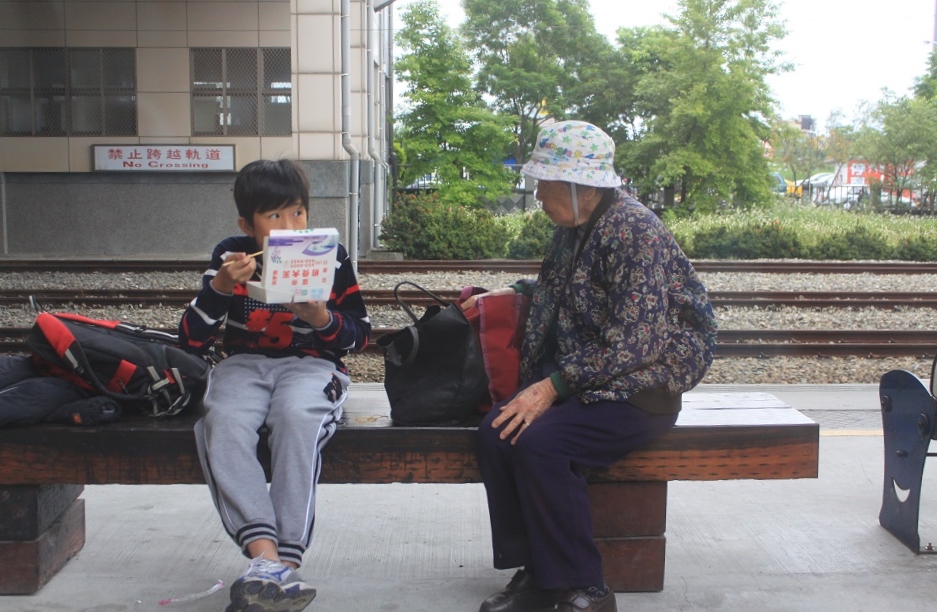 A Young Boy with His Grandmother at a Small Train Station